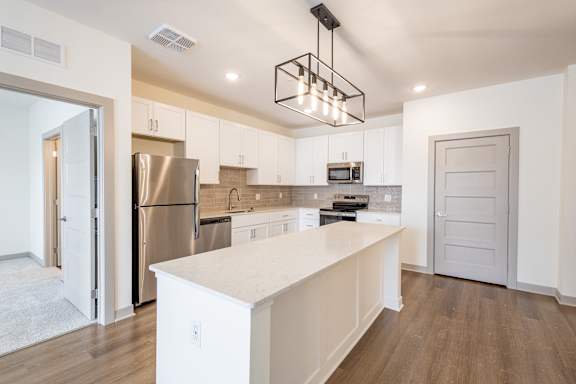 A modern kitchen with a white island and stainless steel appliances.