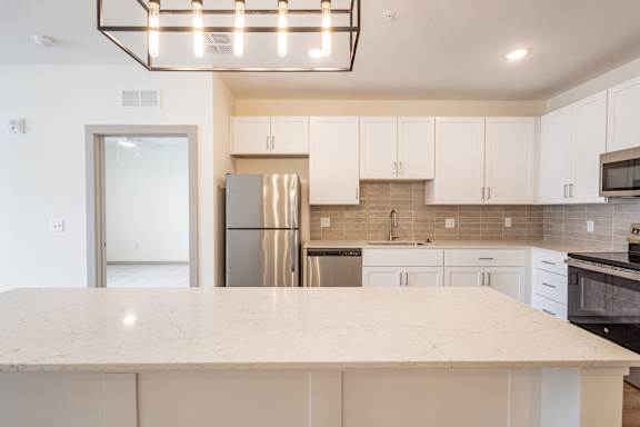 A kitchen with a marble countertop and stainless steel appliances.