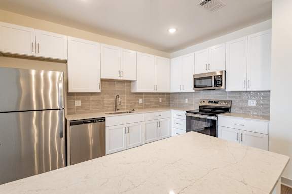A kitchen with a marble counter top and stainless steel appliances.