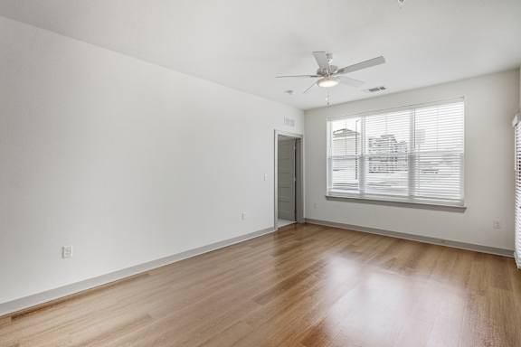 A room with a ceiling fan and a window with blinds.