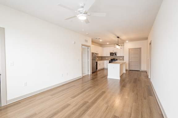 A spacious kitchen with a fan on the ceiling.