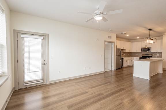 A spacious living room with a kitchen in the background.