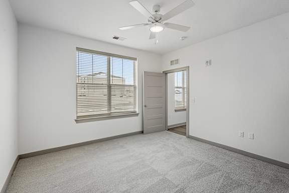 A room with a ceiling fan and a window with blinds.
