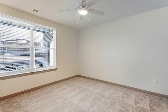 A room with a carpeted floor and a window with blinds.