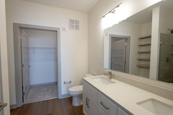 A bathroom with a toilet, sink, and mirror.