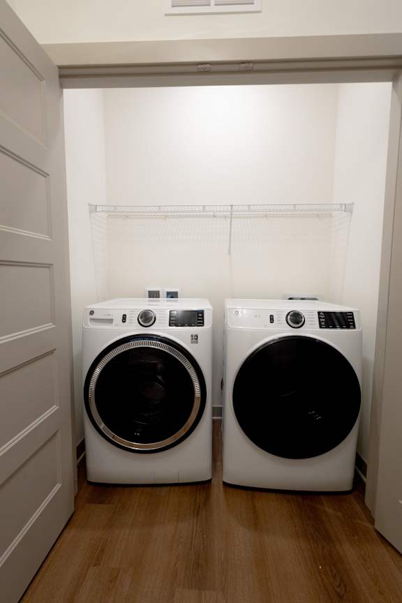 Two white front load washing machines in a laundry room.