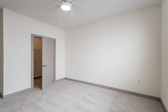 A room with a carpeted floor and a ceiling fan.