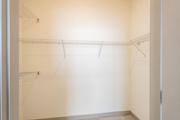Empty white closet with shelves and hangers.