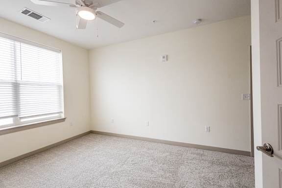A room with a ceiling fan and a window with blinds.