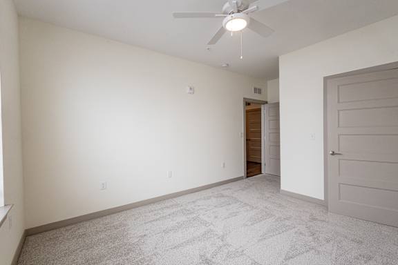 A room with a ceiling fan and a carpeted floor.