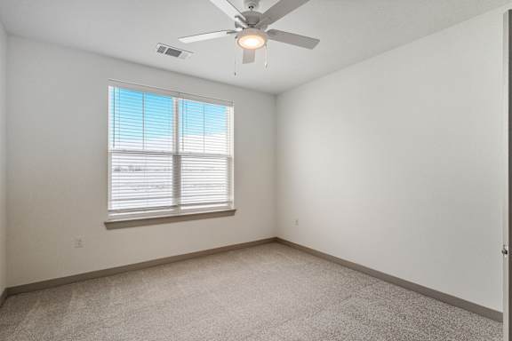 A room with a ceiling fan and a window with blinds.