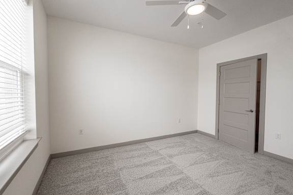 A room with a ceiling fan and a door.
