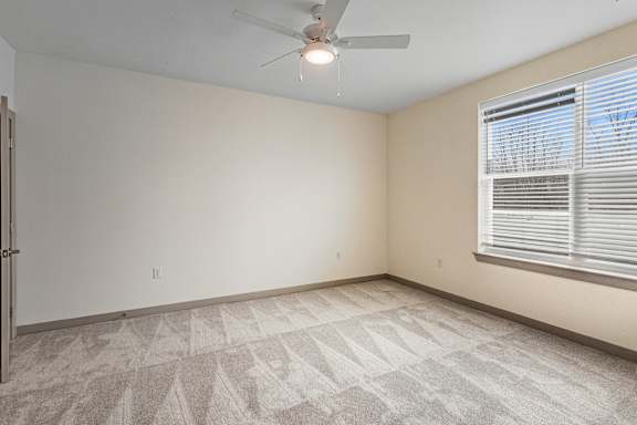 A room with a ceiling fan and a window with blinds.