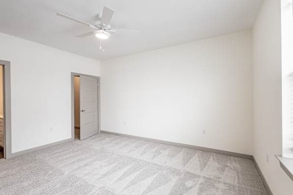 A room with a ceiling fan and carpeted floor.
