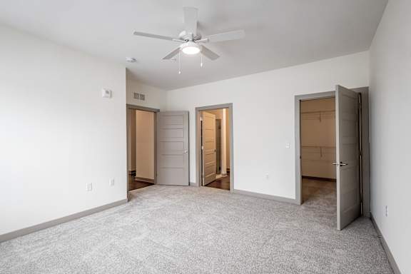 A room with a ceiling fan and three doors.