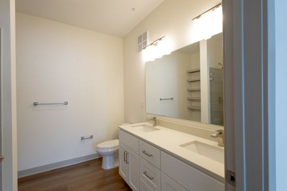A white bathroom with a toilet, sink, and mirror.