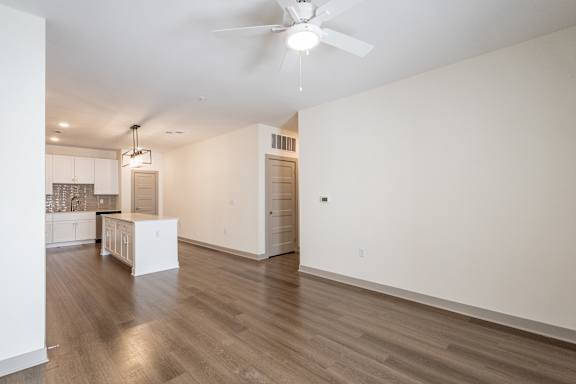 A room with a ceiling fan and wooden flooring.