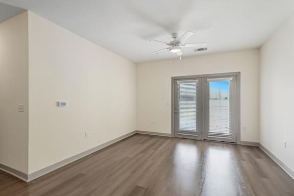 A room with a ceiling fan and sliding glass doors.