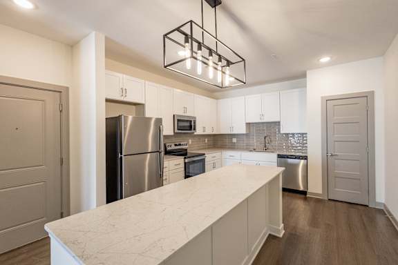 A kitchen with a marble countertop and stainless steel appliances.