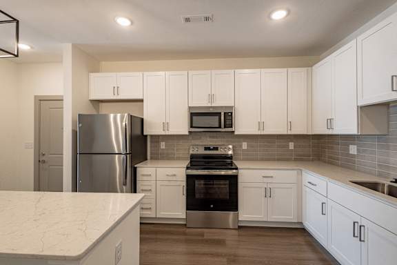 A kitchen with white cabinets and a marble countertop.