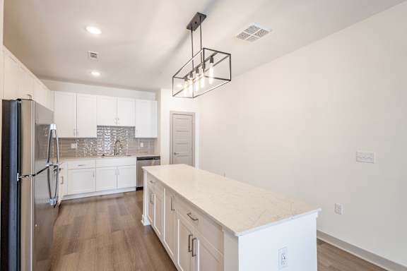 A kitchen with a refrigerator on the left and a counter on the right.