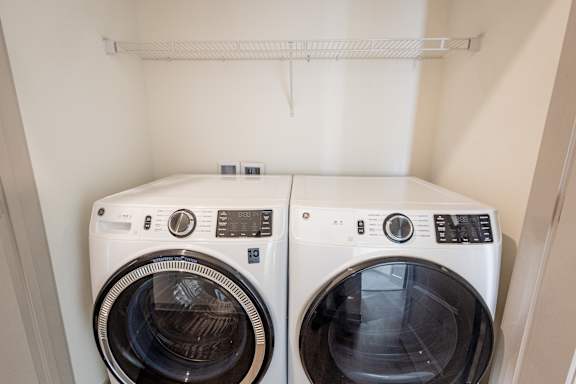 Two white front loading washing machines in a small laundry room.