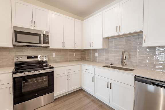 A kitchen with white cabinets and a black oven.