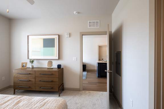 A bedroom with a bed, dresser, and a painting on the wall.