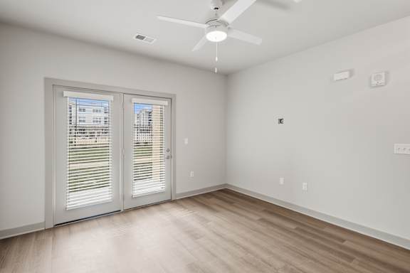 A room with a ceiling fan and a window with blinds.