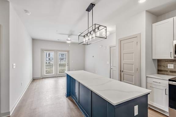 A kitchen with a blue island and white cabinets.