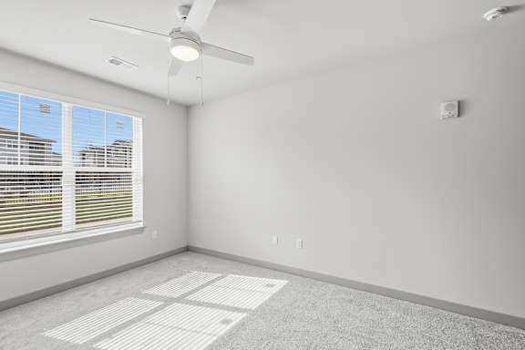 A room with a ceiling fan and a window with blinds.