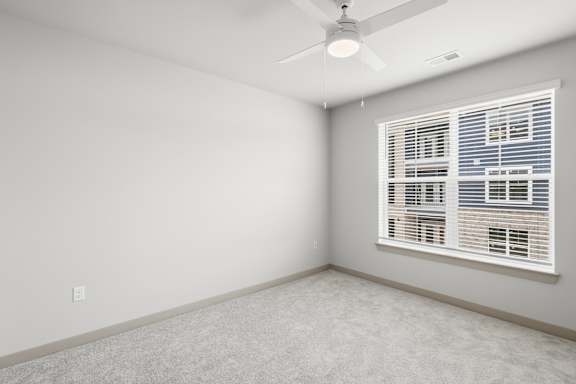 A room with a ceiling fan and a window with blinds.