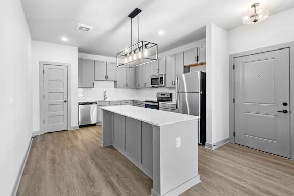 A modern kitchen with a white island and stainless steel appliances. at Arbour Place Apartments, Jeffersonville, Indiana