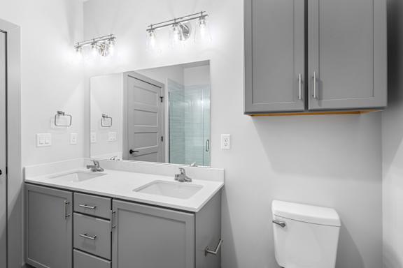 A bathroom with a white toilet, a sink with a mirror above it, and a cabinet above the sink at Arbour Place Apartments, Indiana