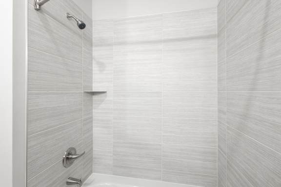 A white tiled shower with a silver faucet at Arbour Place Apartments, Indiana, 47130