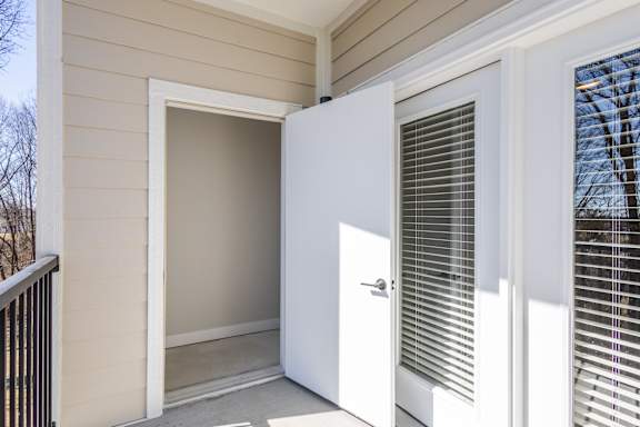 A white door is open to a room with a window at Arbour Place Apartments, Jeffersonville, IN