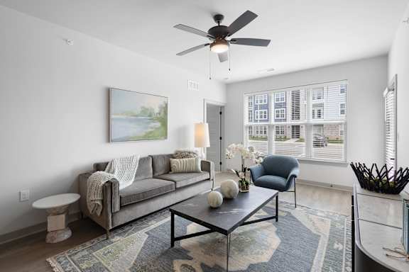 A living room with a grey couch, a coffee table, and a ceiling fan.