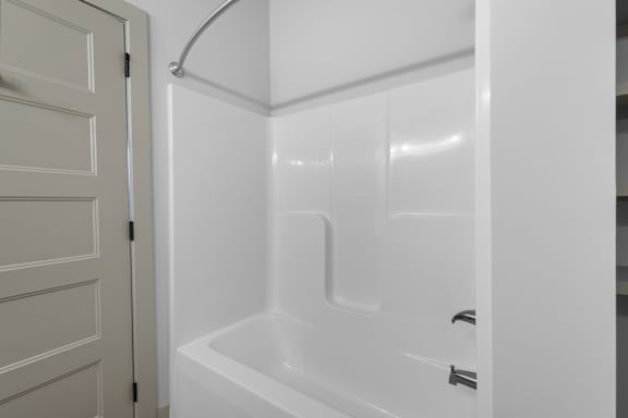 A white bathroom with a tub and shower.at Forest Edge Apartments, Charlestown, IN