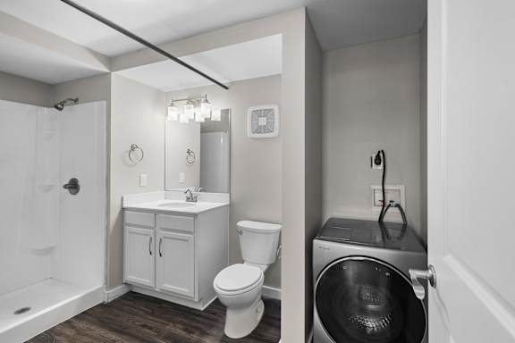 A small bathroom with a toilet, sink, and a washer and dryer.