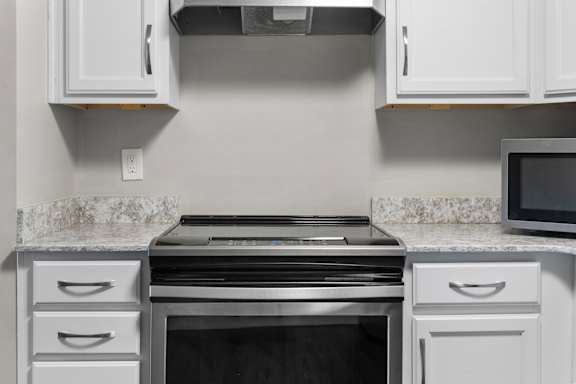A modern kitchen with a stainless steel oven and white cabinets.