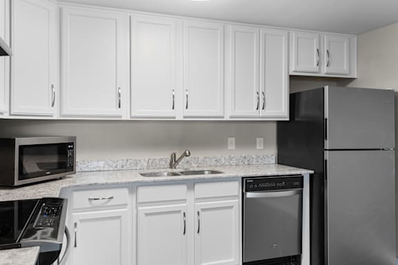 A kitchen with white cabinets and black appliances.