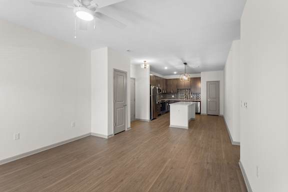 A spacious room with wooden floors and a kitchen area in the background.at Arlington Farms, Greenwood, IN, 46143