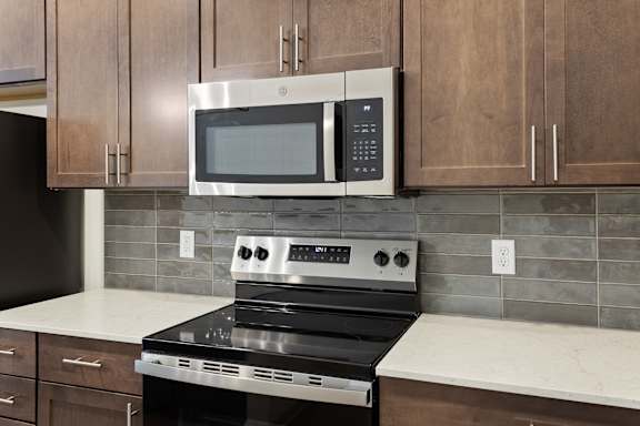 A modern kitchen with a stove and microwave above it.at Arlington Farms, Greenwood Indiana