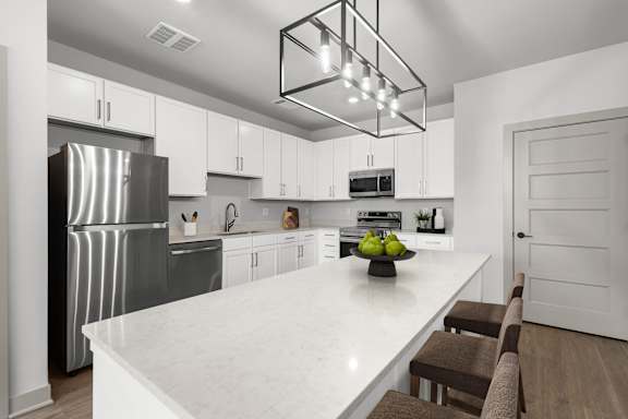 A modern kitchen with a white marble countertop and stainless steel appliances.at Forest Edge Apartments, Charlestown, IN