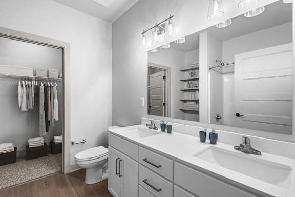 A bathroom with a white toilet, sink, and mirror.at Forest Edge Apartments, Indiana