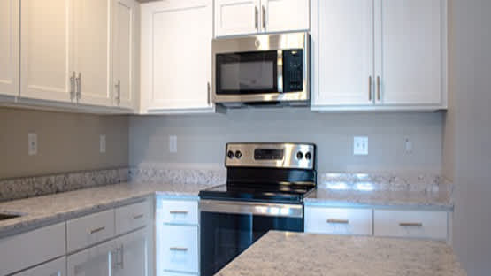 Modern kitchen with white cabinets and granite countertops at Current812 Apartments, Clarksville, IN 47129