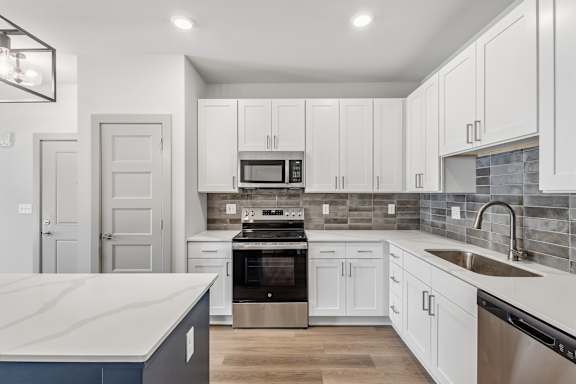 A modern kitchen with white cabinets and a marble countertop.
