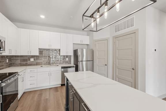 A modern kitchen with white cabinets and a large island.