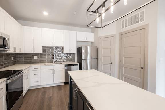 A modern kitchen with white cabinets and a wooden floor.