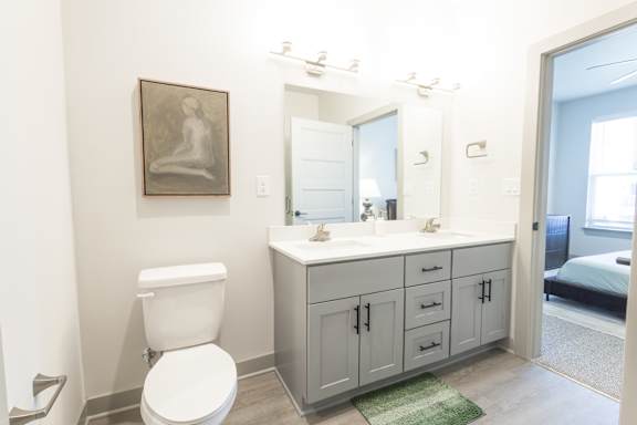 A bathroom with a toilet, sink, and a picture on the wall.